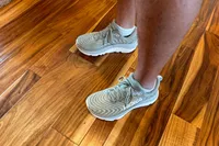 A person stands on a hardwood floor while wearing the Hoka's Men's Gaviota 5 Running Shoes
