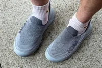A person wears the Hoka Restore TC Recovery Shoes on concrete