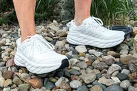 A person walks outside on pebbles while wearing the Hoka Women's Bondi SR Road Shoe