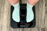 A person stands on the HumeHealth The Body Pod