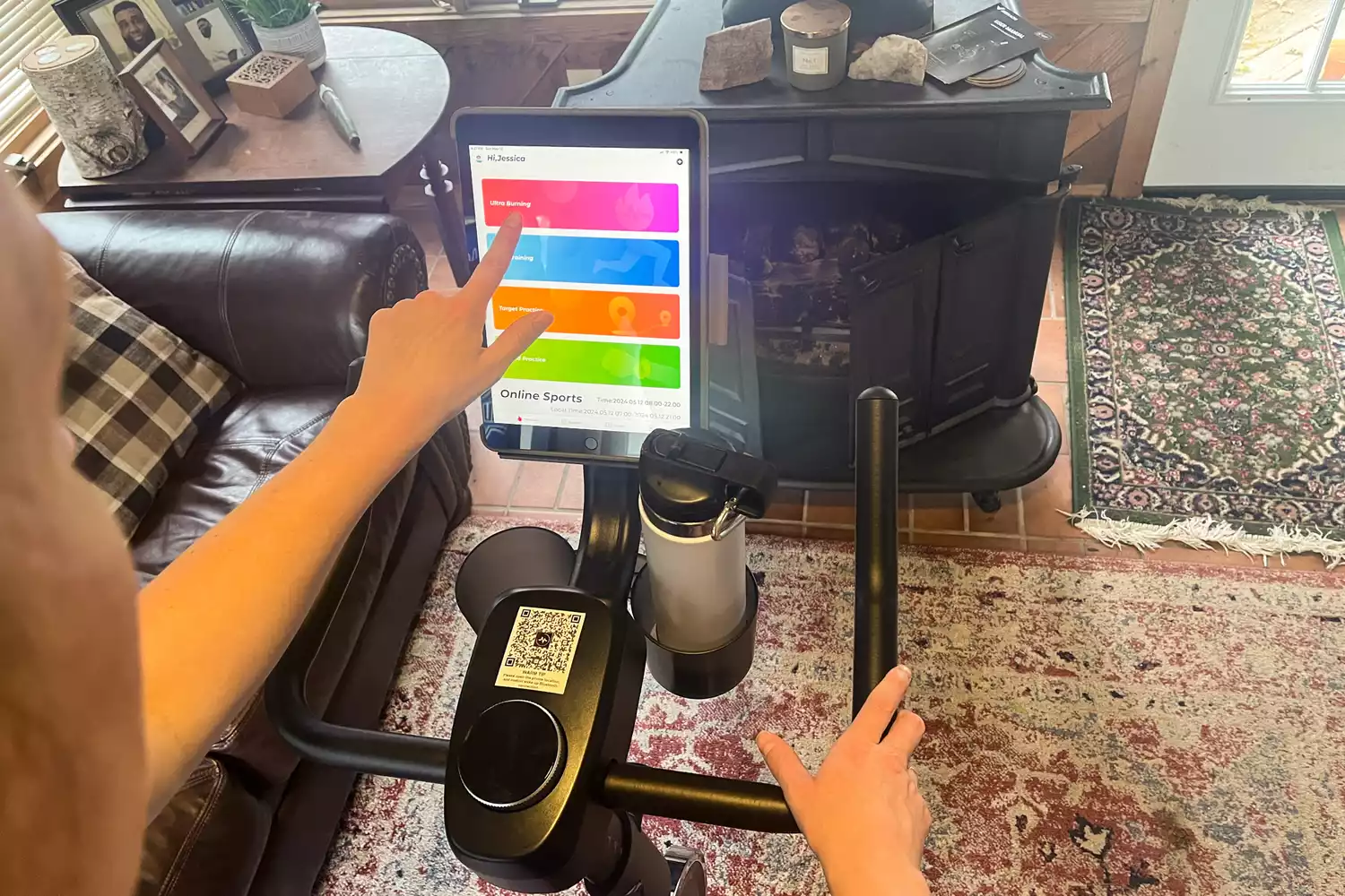 A person touches the digital display on the Merach S26 Exercise Bike