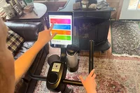A person touches the digital display on the Merach S26 Exercise Bike