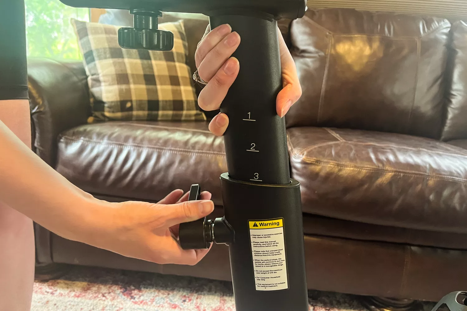 A person adjusts the seat on the Merach S26 Exercise Bike