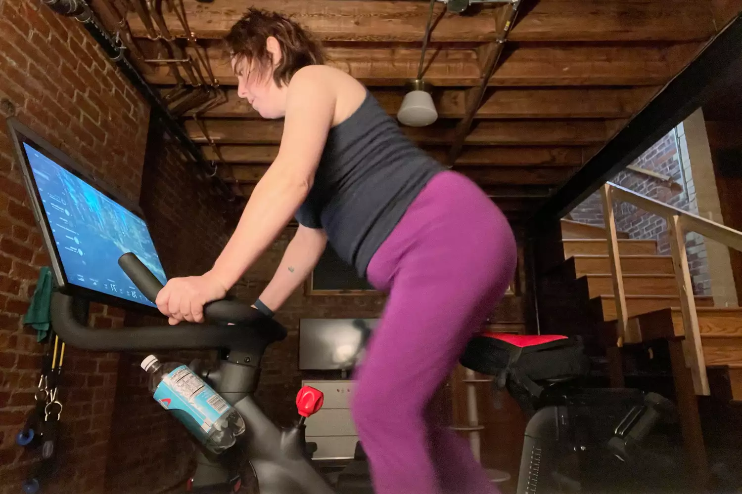 A person exercising on Peloton Bike + Essentials in a basement