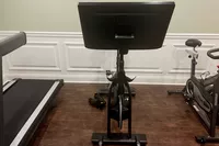 Equinox+ SoulCycle At-Home Bike on hardwood floor between treadmill and another stationary bike