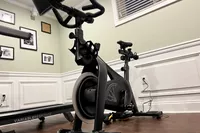 Equinox+ SoulCycle At-Home Bike on hardwood floor near treadmill