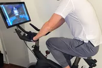 Person riding the Stryde The Bike with trainer on screen