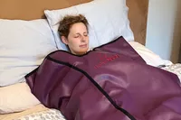 Person laying on a bed in the HigherDose Infrared Sauna Blanket