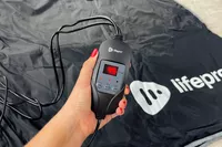 A person holds the control panel for the LifePro BioRemedy Infrared Sauna Blanket