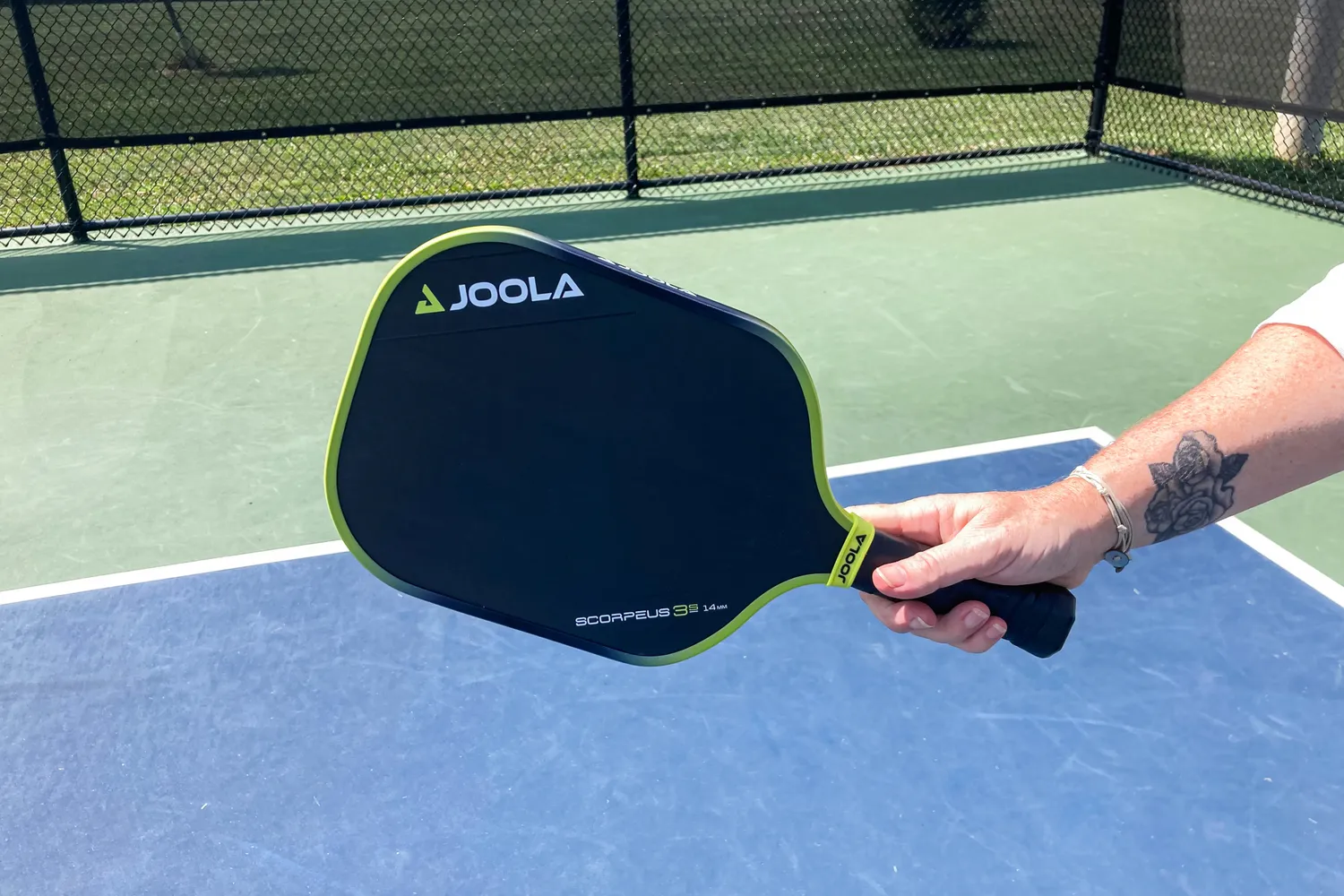 A person holds up the JOOLA Anna Bright Scorpeus 3S 14mm Pickleball Paddle