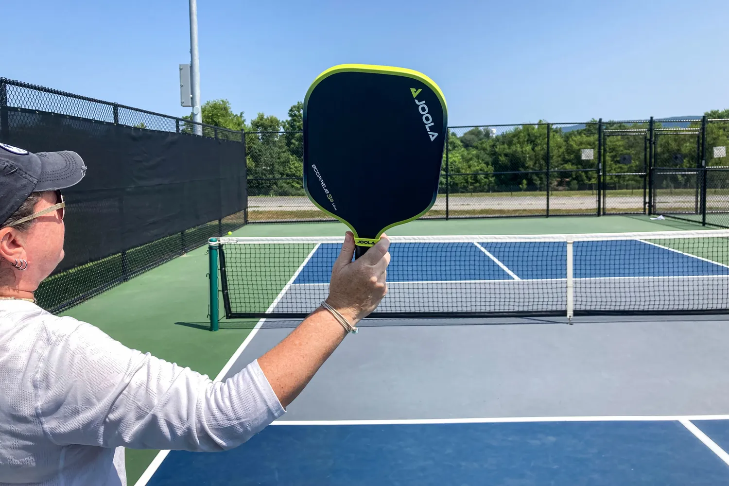 A person holds up the JOOLA Anna Bright Scorpeus 3S 14mm Pickleball Paddle