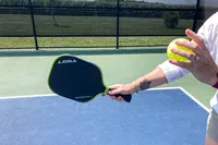 A person prepares to hit a pickleball with the JOOLA Anna Bright Scorpeus 3S 14mm Pickleball Paddle