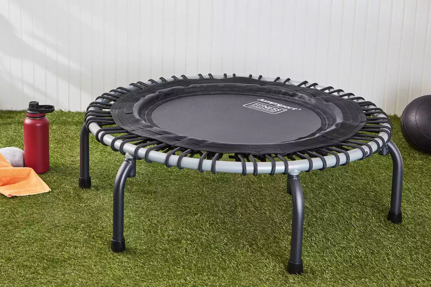 JumpSport 350 Indoor Fitness Trampoline displayed on grass next to water bottle and ball