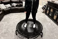 A person stands on the JumpSport 550f 44-Inch Pro Rebounder Trampoline