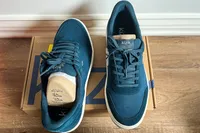 A pair of Kizik Men's Prague 2 Sneakers on a shoebox