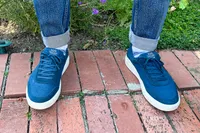 A person wears the Kizik Men's Prague 2 Sneakers outside on brick