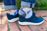 A person slips their heel out of the Kizik Men's Prague 2 Sneakers