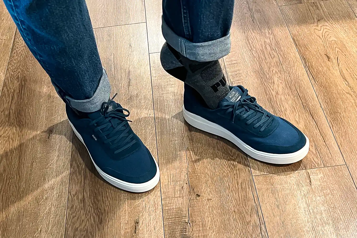 An overhead view of a person wearing the Kizik Men's Prague 2 Sneakers on a wooden floor