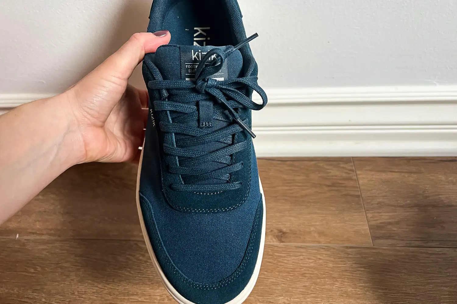 A person holds up the Kizik Men's Prague 2 Sneaker