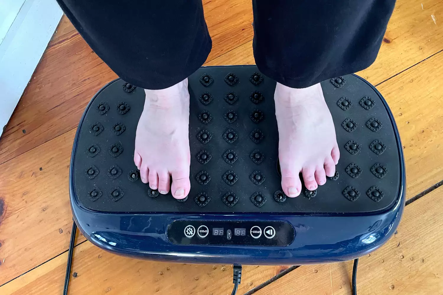 A person stands on the LifePro HexaPlate Lite Vibration Plate
