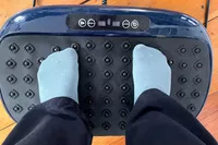 A person stands on the LifePro HexaPlate Lite Vibration Plate in socks