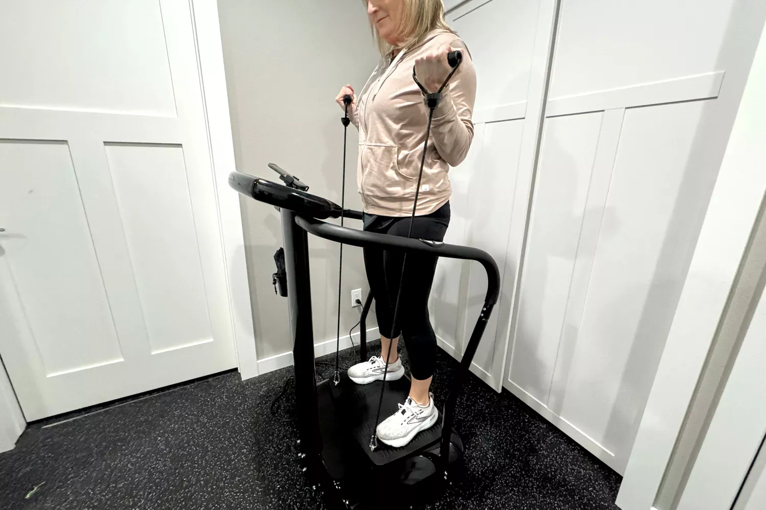 A person uses the resistance arm bands on the Lifepro Rhythm Vibration Plate