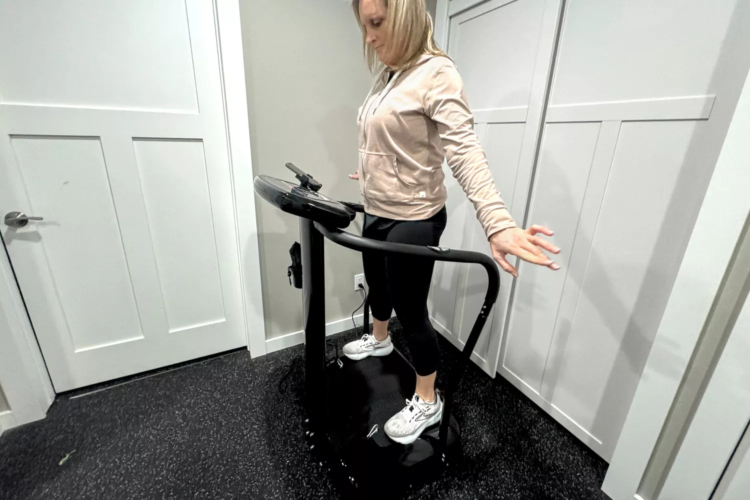 A person stands on the Lifepro Rhythm Vibration Plate with their arms out