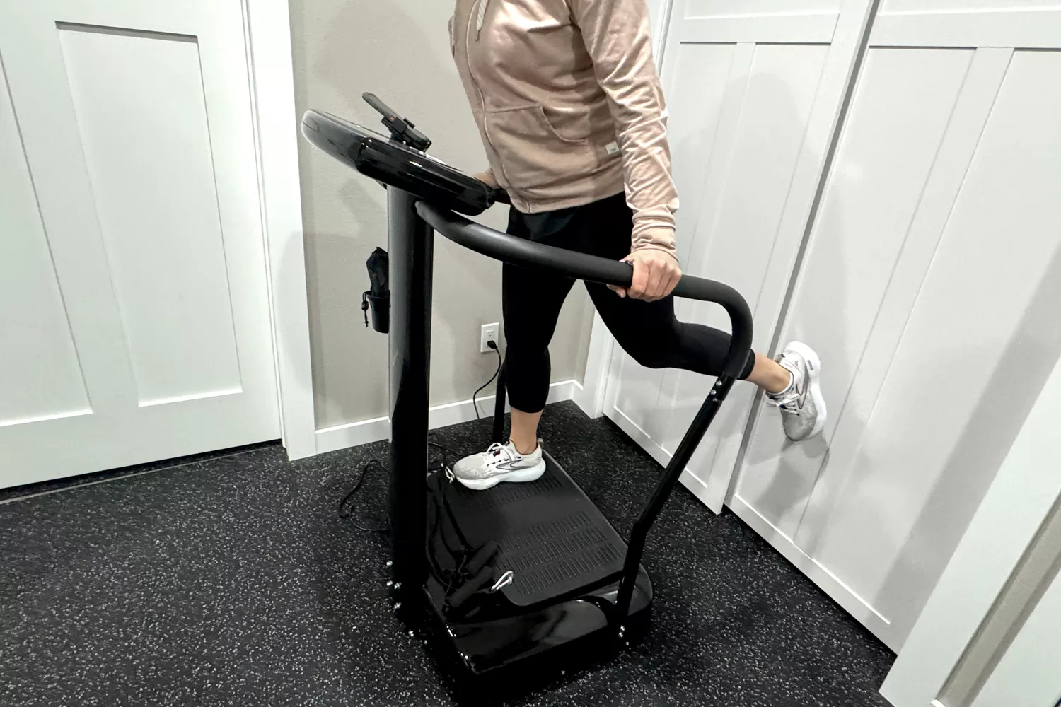 A person stands on the Lifepro Rhythm Vibration Plate on one leg
