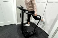A person stands on the Lifepro Rhythm Vibration Plate on one leg