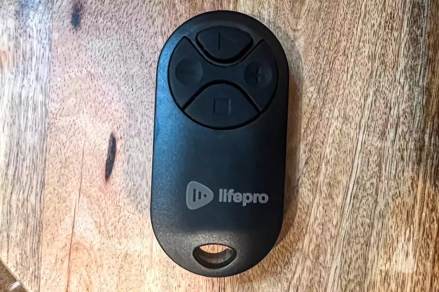 A close-up of the remote for the LifePro TimberTrek Treadmill on a wooden surface