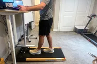 A person walking on the LifePro TimberTrek Treadmill while using a standing desk
