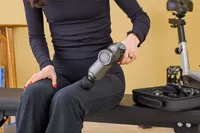A person using the RENPHO Power Massage Gun on their leg