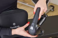 A person showing the back of the Theragun Prime