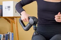 A person using the Theragun Prime on their thigh