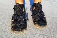 A close up of a person's sand-covered feet wearing the KEEN Men's H2 Water Sandals
