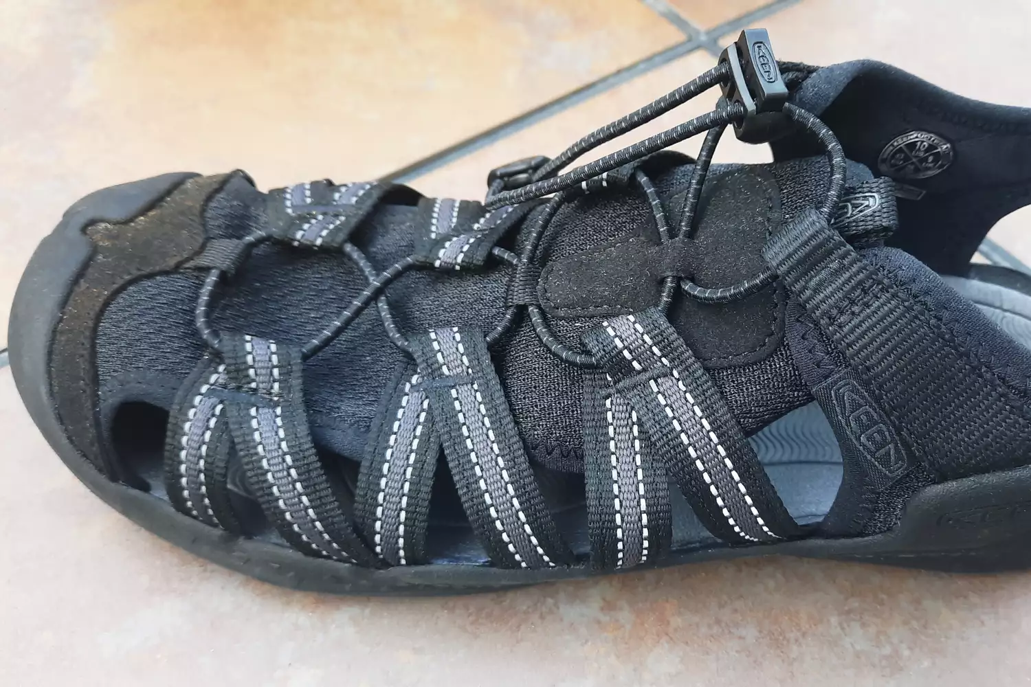 A close up of the KEEN Men's H2 Water Sandal on tile floor