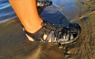 A close up of a person wearing the KEEN Men's H2 Water Sandals on a beach