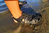 A close up of a person wearing the KEEN Men's H2 Water Sandals on a beach