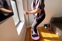 A person squats while standing on the Merach Whole Body Vibration Plate