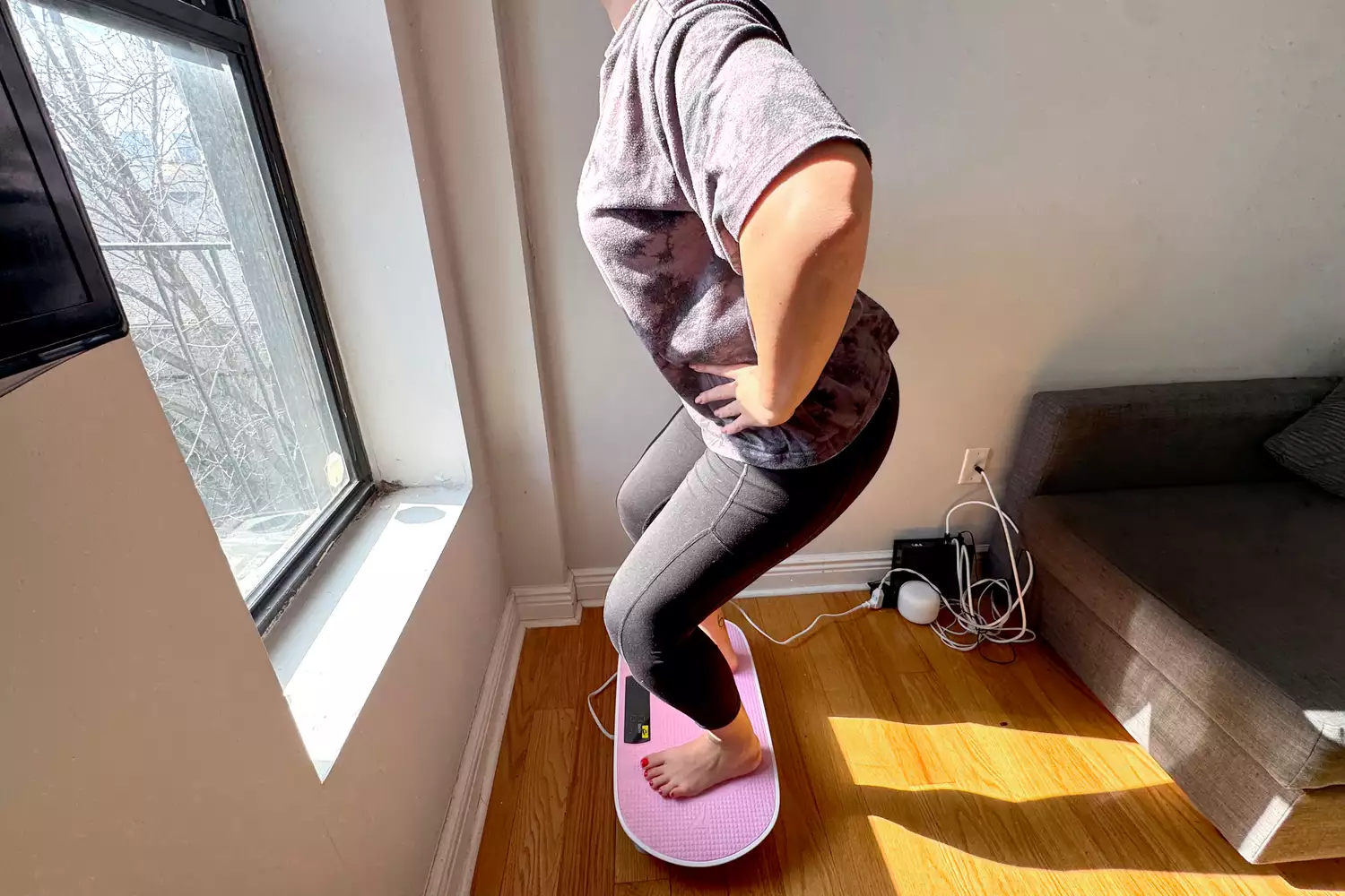 A person squats on the Merach Whole Body Vibration Plate