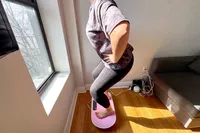 A person squats on the Merach Whole Body Vibration Plate