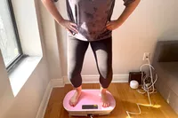A person squats on the Merach Whole Body Vibration Plate