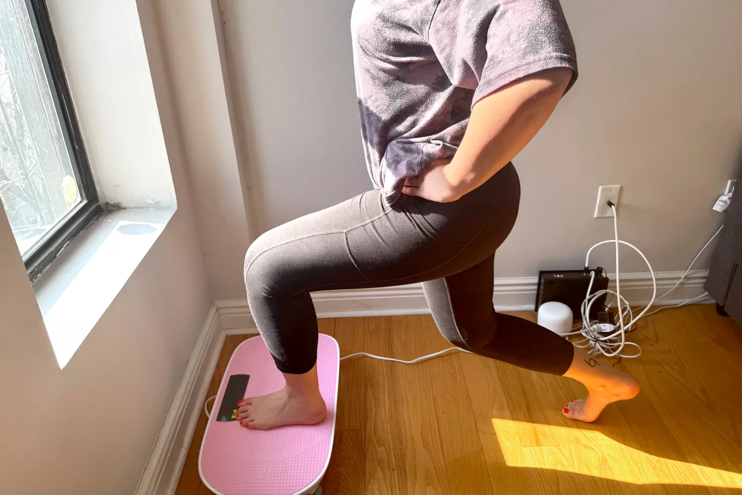 A person squats on the Merach Whole Body Vibration Plate