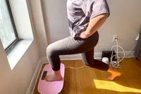 A person squats on the Merach Whole Body Vibration Plate