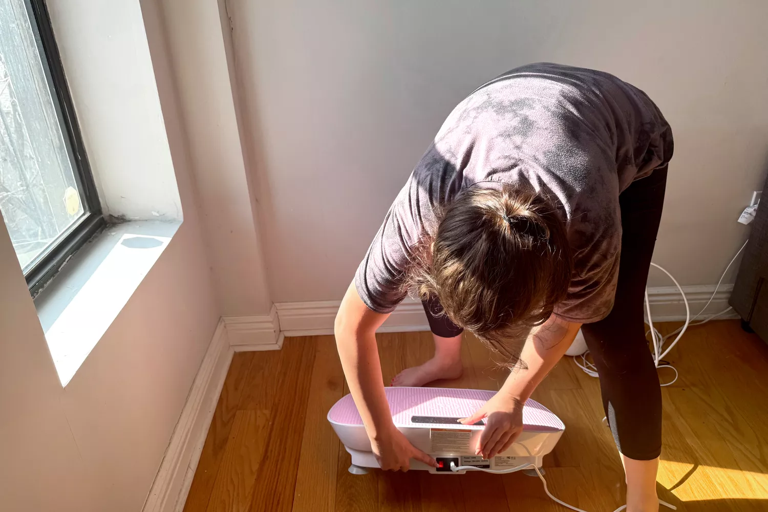 A person pushes a button on the Merach Whole Body Vibration Plate