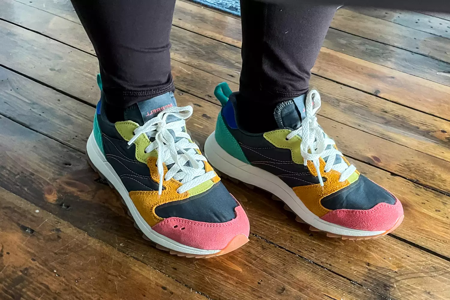 A close-up of the Merrell Women's Alpine 83 Sneaker Sport sneakers worn on a wooden floor