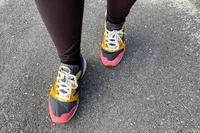 An overhead view of a legs walking on a road while wearing the Merrell Women's Alpine 83 Sneaker Sport