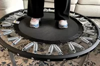 A person stands on the Needak Soft-Bounce Folding Rebounder