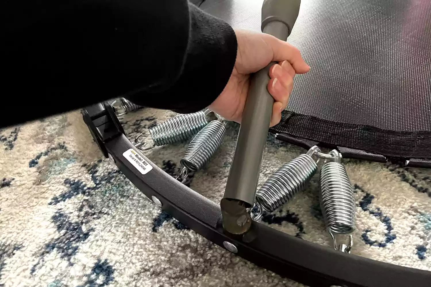 A person folds the leg of the Needak Soft-Bounce Folding Rebounder toward the mat