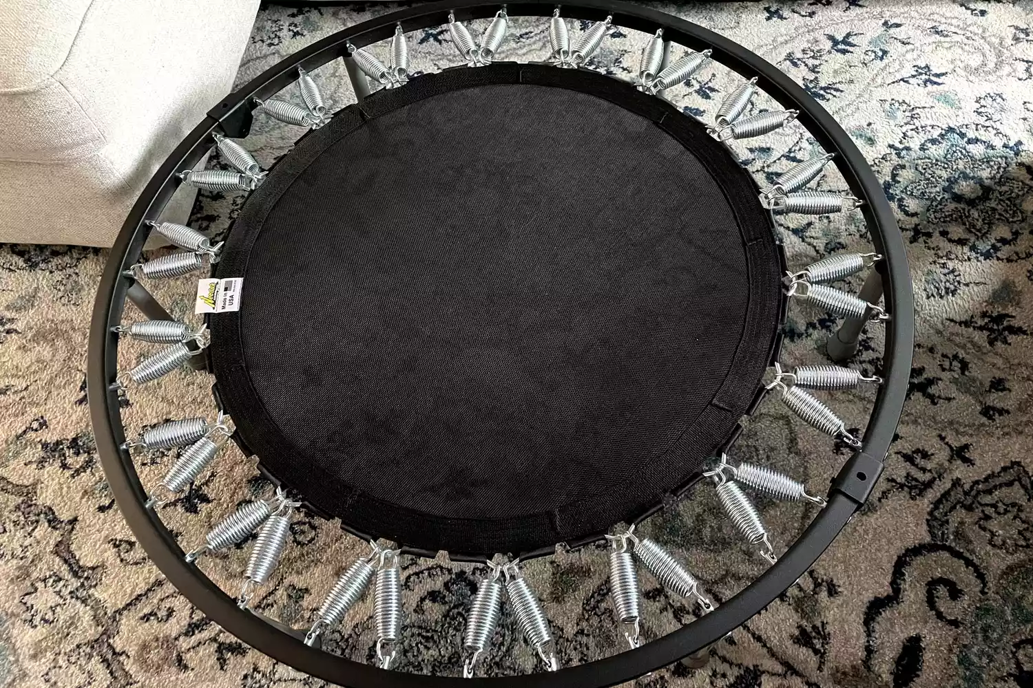 The Needak Soft-Bounce Folding Rebounder extended on a colorful carpet
